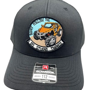 Puede incluir: Gorra de camionero negra con un parche bordado en blanco y negro que dice "Don't Follow The I Do Stupid Things" y una imagen de dibujos animados de un vehículo todoterreno amarillo. La gorra es ajustable y tiene una etiqueta Richardson 112.