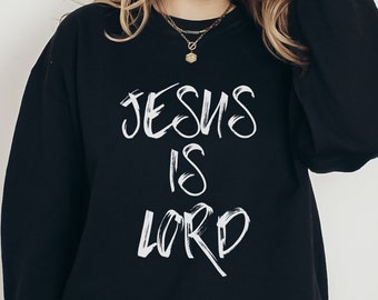 May include: Black sweatshirt with white text that reads "JESUS IS LORD" in a handwritten style.