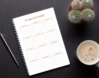 Puede incluir: Una agenda anual blanca con el título "YEARLY PLANNER" en rojo y una encuadernación en espiral. La agenda está dividida en 12 secciones, una para cada mes del año. Cada sección tiene un fondo marrón claro y está etiquetada con el nombre del mes.