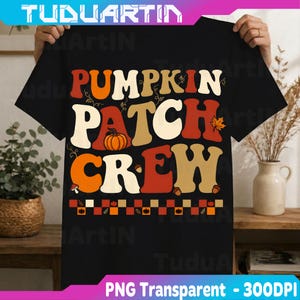 May include: A black short-sleeve t-shirt featuring the text PUMPKIN PATCH CREW in large, retro-style orange, cream, and red letters. The design includes a small orange pumpkin, autumn leaves, acorns, and a checkered border at the bottom.