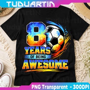 Könnte beinhalten: Ein schwarzes Kurzarm-T-Shirt mit einem Grafikdruck eines Fußballs neben einer großen Zahl 8. Der Text lautet 8 YEARS OF BEING AWESOME in einer farbenfrohen Gradientenschrift mit blauen, gelben und orangen Farbtönen auf dem schwarzen Stoff.