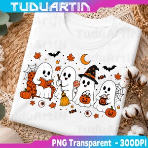 May include: A white t-shirt featuring a graphic print of four cartoon ghosts celebrating Halloween. The design includes ghosts reading a book, holding a broom, wearing a witch hat, and holding a pumpkin mug, surrounded by bats, maple leaves, and candy.