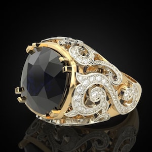 Op de afbeelding: Een gouden en zilveren ring met een grote, donkerblauwe edelsteen gezet in een decoratieve, sierlijke setting. De ring heeft een zwierig, bloemig ontwerp met kleine, heldere edelstenen.