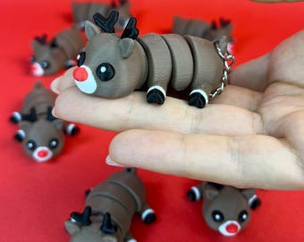 May include: A set of five brown and black segmented reindeer keychains with red noses and white accents. The reindeer are posed in a curled up position.