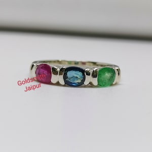 Könnte beinhalten: Ein silberner Ring mit drei ovalen Edelsteinen. Die Edelsteine sind rot, blau und grün.