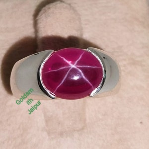 Peut inclure: Une bague en argent avec une grande pierre précieuse de rubis étoilé rouge ronde.