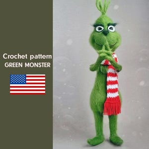 Puede incluir: Una figura de monstruo verde tejido a ganchillo con ojos blancos, una bufanda a rayas rojas y blancas y una expresión traviesa. La figura se lleva los dedos a la boca. El texto "Crochet pattern GREEN MONSTER" es visible.