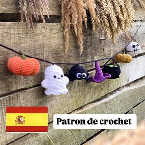 May include: A Halloween-themed crochet garland featuring a pumpkin, ghost, spider, witch's hat, cauldron, and skull. The handmade decorations are in orange, white, black, and purple. The garland is strung on a black cord and displayed against a wooden background.