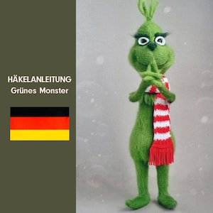 Puede incluir: Un monstruo verde de crochet con una bufanda a rayas rojas y blancas. El monstruo tiene una expresión gruñona y está de pie sobre un fondo blanco. El texto "HÄKELANLEITUNG Grünes Monster" es visible en la imagen.