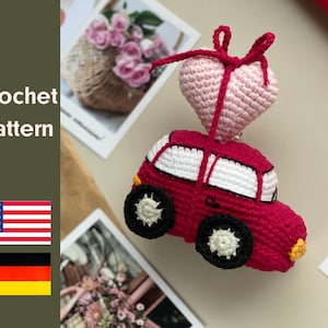 Puede incluir: Patrón de crochet para un coche rojo con un corazón rosa en la parte superior. El coche tiene ventanas blancas y ruedas negras. El corazón tiene un lazo rosa.