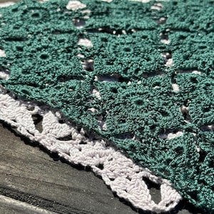 May include: A green and white crocheted doily with a delicate lace pattern.