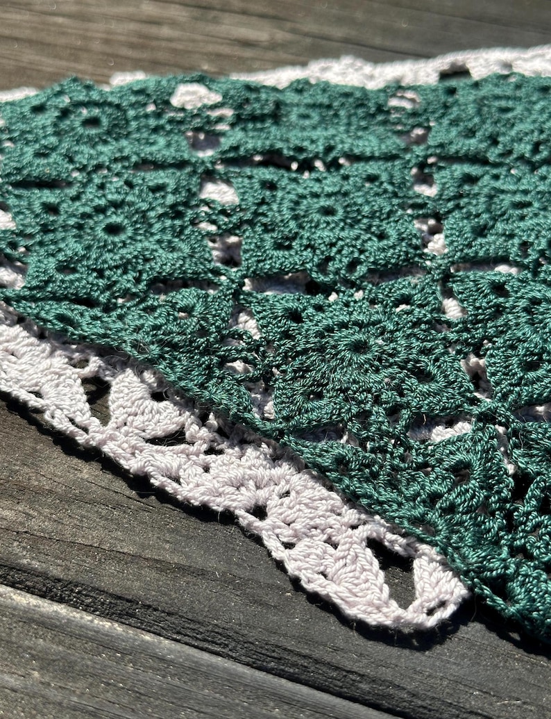 May include: A green and white crocheted doily with a delicate lace pattern.