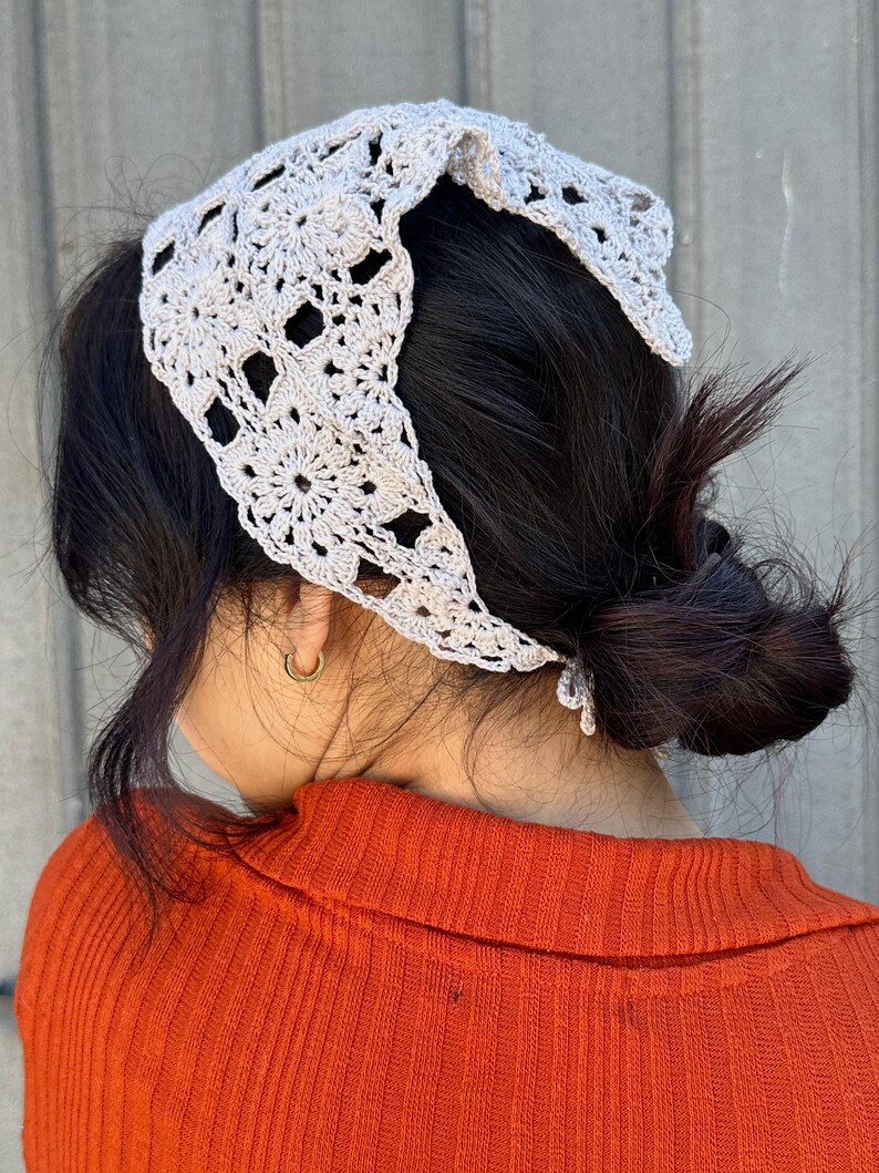 May include: A light gray crocheted headband with a square pattern. The headband is tied in a knot at the back of the head.