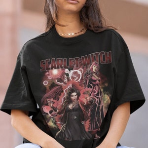 Peut inclure: T-shirt noir avec un imprim&eacute; graphique de Scarlet Witch de Marvel Comics. Le graphique pr&eacute;sente trois versions de Scarlet Witch dans diff&eacute;rentes poses, avec des accents rouges et violets. Le texte "SCARLET WITCH" est imprim&eacute; en blanc au-dessus du graphique.