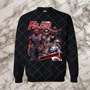 May include: Black sweatshirt featuring a graphic print of Falcon and Winter Soldier characters from the Marvel Cinematic Universe. The print shows the characters in action poses with the words "FALCON" and "WINTER SOLDIER" in red and white text.