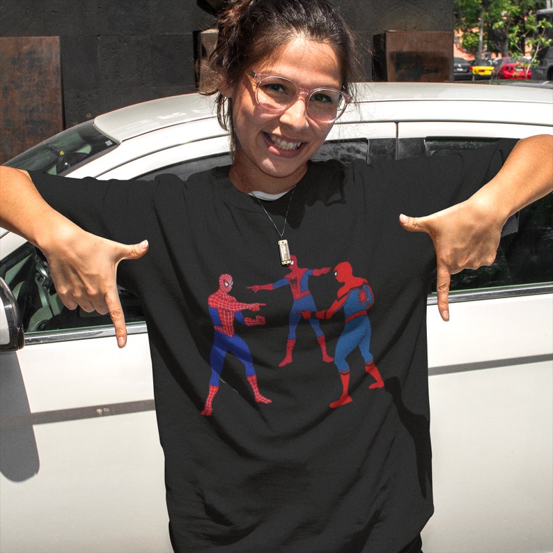 May include: A black t-shirt with a graphic of three Spider-Man characters in a pointing meme. The characters are red and blue with black outlines.