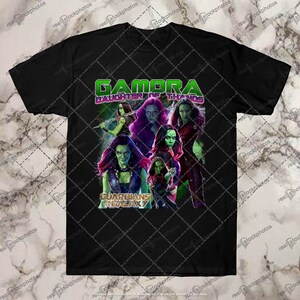 May include: Black t-shirt with a graphic of Gamora from Guardians of the Galaxy. The graphic features Gamora in different poses with the text "Gamora Daughter of Thanos" and "Guardians of the Galaxy".