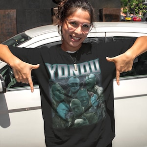 May include: Black t-shirt with a graphic print of a group of blue-skinned characters from the movie Guardians of the Galaxy. The text "Yondou" is printed in silver above the characters.