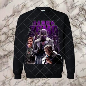 Op de afbeelding: Zwart sweatshirt met een paarse en witte grafische print van Baron Zemo uit het Marvel Cinematic Universe. De afbeelding toont Zemo's masker en een groep personages uit de show.