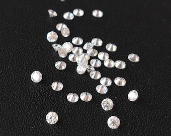 May include: A scattering of small, clear, round diamonds on a black surface.