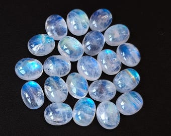May include: A collection of oval-shaped moonstone cabochons, with a milky white color and iridescent blue and green flashes.
