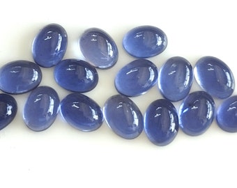 May include: A group of 15 oval-shaped, translucent, light blue glass cabochons. The cabochons are smooth and shiny.