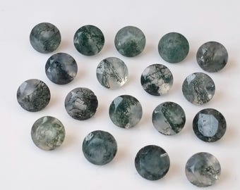 May include: A collection of 18 round, green moss agate cabochons. The stones are translucent and have a variety of green and white patterns.