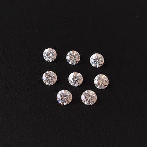 Könnte beinhalten: Neun klare runde Edelsteine auf schwarzem Hintergrund. Die Edelsteine sind in Form eines Diamanten angeordnet.