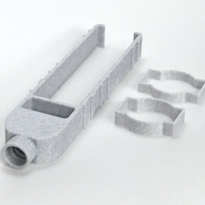 May include: A light gray plastic tool with a long, U-shaped handle and a rectangular opening. Two matching, smaller, curved-edge pieces are also present. The tool has a speckled texture and a cylindrical end.