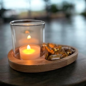 May include: A wooden candle holder with a glass cover, holding a lit tea light candle. The holder also has a section filled with wrapped candies. The wood has a natural grain, and the glass is clear.