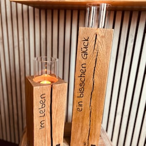 May include: Two wooden candle holders with glass inserts. The holder on the left has the text "im Leben" carved into it. The holder on the right has the text "ein bisschen glück" carved into it.