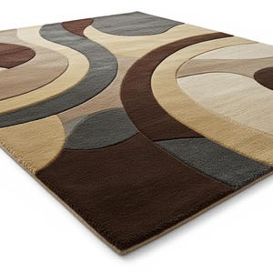 A high-angle shot of a rectangular hand-tufted wool area rug featuring a modern abstract pattern in brown, beige, tan, and grey. The rug is placed on a light oak wood floor in a bright living room next to a cream sofa, potted plants, and a wooden coffee table.
