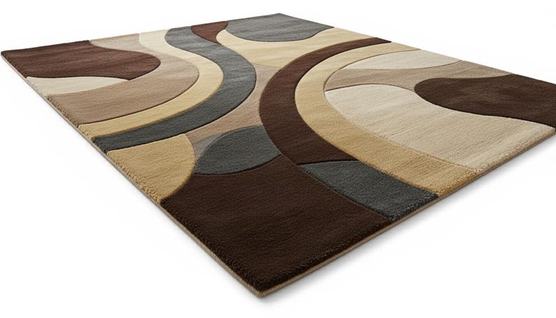 A high-angle shot of a rectangular hand-tufted wool area rug featuring a modern abstract pattern in brown, beige, tan, and grey. The rug is placed on a light oak wood floor in a bright living room next to a cream sofa, potted plants, and a wooden coffee table.