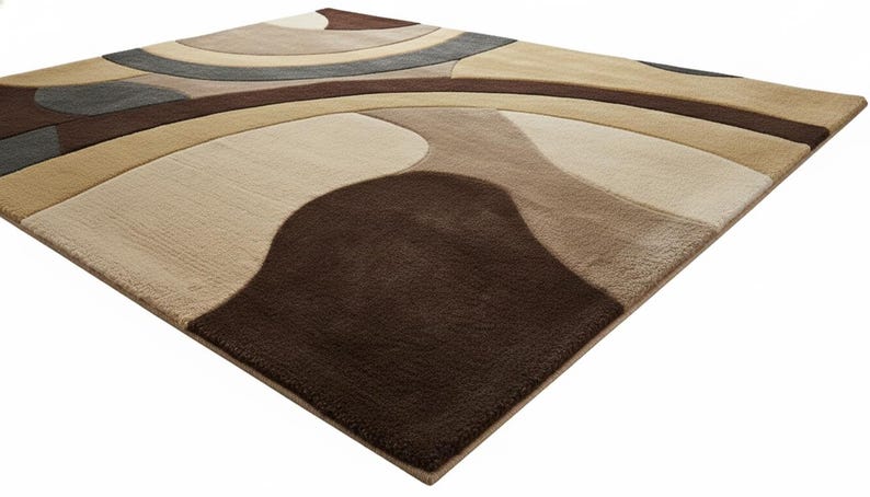 A high-angle shot of a rectangular hand-tufted wool area rug featuring a modern abstract pattern in brown, beige, tan, and grey. The rug is placed on a light oak wood floor in a bright living room next to a cream sofa, potted plants, and a wooden coffee table.