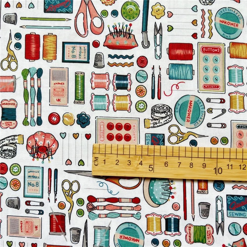 May include: White fabric with a repeating pattern of sewing and crafting supplies, including spools of thread, buttons, needles, scissors, thimbles, and measuring tape. The text "Dressmaker Pins", "Makower Pins", and "Buttons" are visible on the fabric.