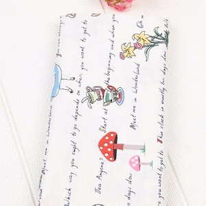 May include: White fabric with a whimsical Alice in Wonderland design. The fabric features text that reads "Which way you ought to go depends on when you want to get to", "Start at the beginning and when you", "Meet me in Wonderland Oh", "Tea Anyone?", and "This clock is exactly two days slow". The fabric also features illustrations of a teacup, teapot, mushrooms, and flowers.