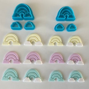Puede incluir: Un conjunto de cortadores de galletas con forma de arcoíris y nube en varios colores. Los cortadores son en tonos azules, amarillos, rosas y verdes. La imagen incluye tanto los cortadores de plástico como las formas recortadas.