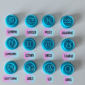 Op de afbeelding: Twaalf blauwe plastic koekjesvormen in de vorm van de astrologische tekens: Schorpioen, Kreeft, Vissen, Waterman, Steenbok, Tweelingen, Maagd, Stier, Boogschutter, Ram, Leeuw en Weegschaal.