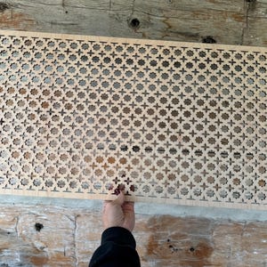 Op de afbeelding: Een houten roosterpaneel met een herhalend geometrisch patroon. Het paneel is lichtbruin en heeft een gladde afwerking.