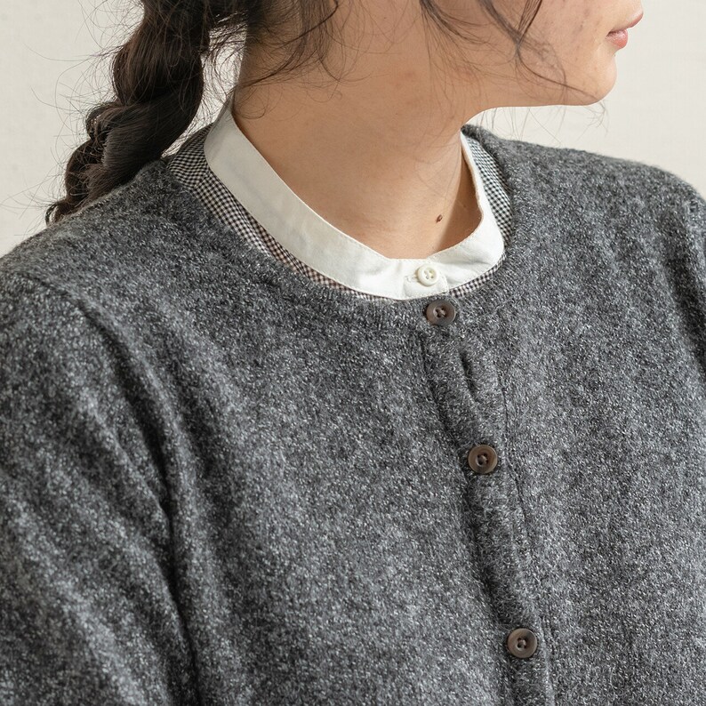 May include: A gray cardigan with a white collared shirt underneath. The cardigan has a button-up front and a textured knit.