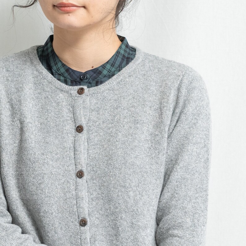 May include: A gray cardigan with a button-up front. The cardigan is made of a soft, fuzzy material.