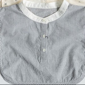 May include: A white and black striped cotton bib with a rounded neckline and three buttons down the front.