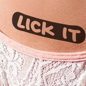 LICK IT tatouage temporaire sexy et coquin en noir. Voulez-vous obtenir une stimulation supplémentaire ?