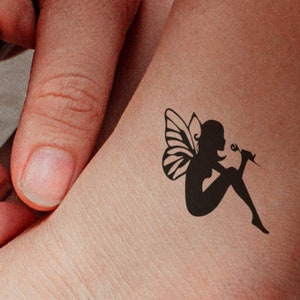 FAIRY holding a FLOWER temporary tattoo in black. She is clever, playful, and having magical powers! Do you believe in fairies?