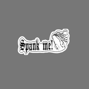 May include: A black and white sticker featuring the text Spank me! in a gothic font, accompanied by a line art illustration of a hand holding a multi-tailed whip. The design has a white border and is set against a solid grey background.
