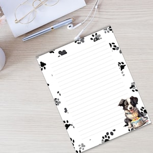 May include: A white lined notepad with a black and gray paw print border. A black and white border collie puppy is sitting on a birthday cake with candles.