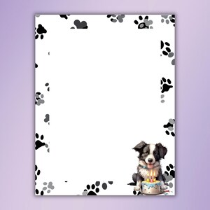 May include: A black and white border collie puppy sits with a birthday cake with candles. The background is white with black paw prints.