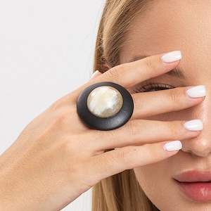 May include: A large, round ring with a black wooden base and a white and brown horn center.