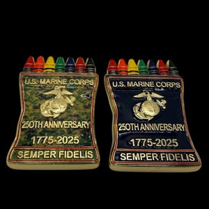 Op de afbeelding: Twee herdenkingsspelden met een ontwerp van een kleurpotlooddoos. Eén speld heeft een camouflage-achtergrond, de andere is marineblauw. Beide tonen het embleem van het U.S. Marine Corps, de tekst "250th Anniversary 1775-2025" en "Semper Fidelis".