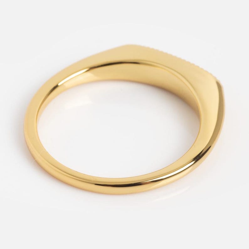 May include: A polished gold ring with a smooth, rounded band and a flat, rectangular top surface. The metal has a reflective, high-shine finish that catches the light, creating a clean, continuous loop design with no visible stones or engravings.